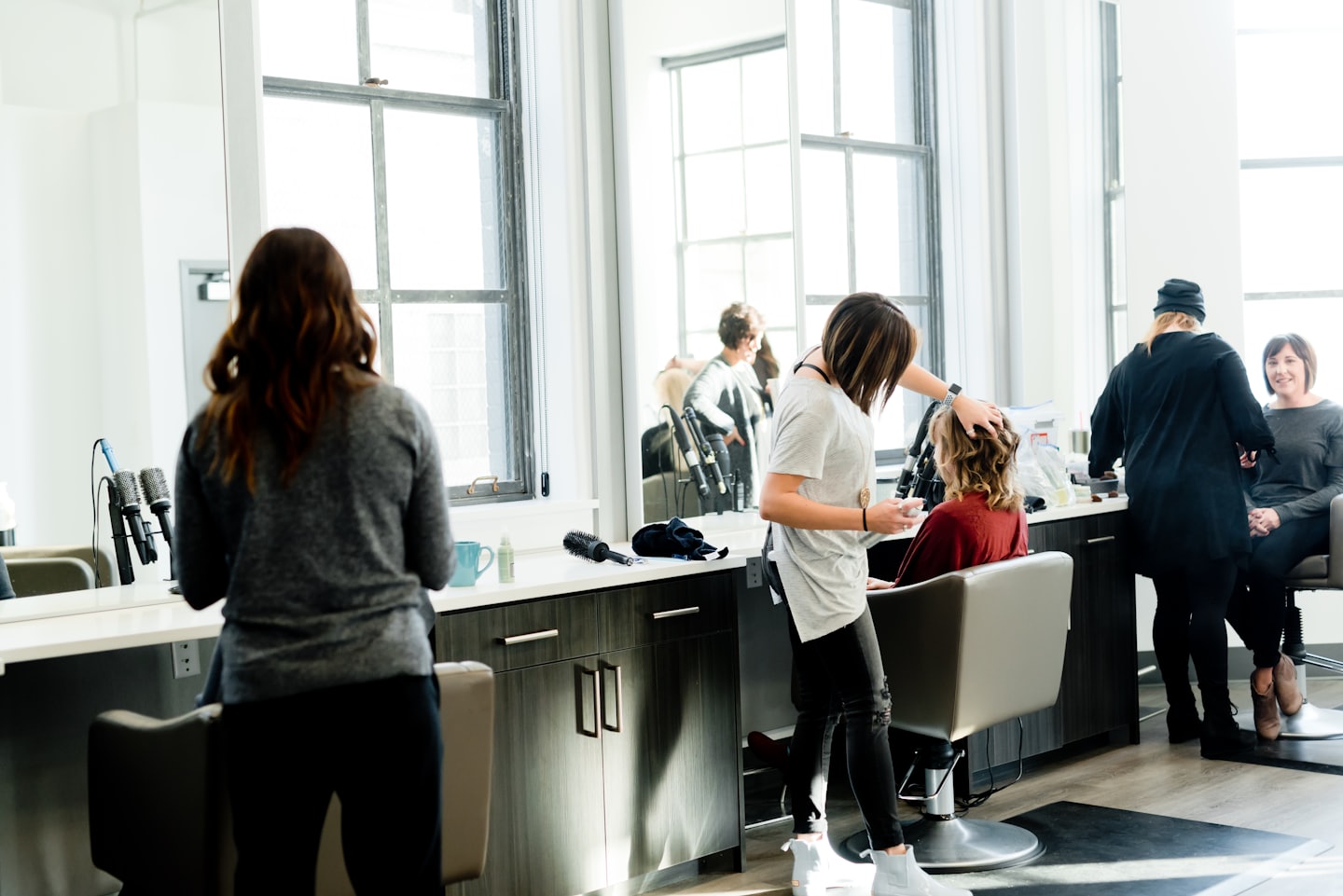 Stylist styling client's hair in a modern salon.