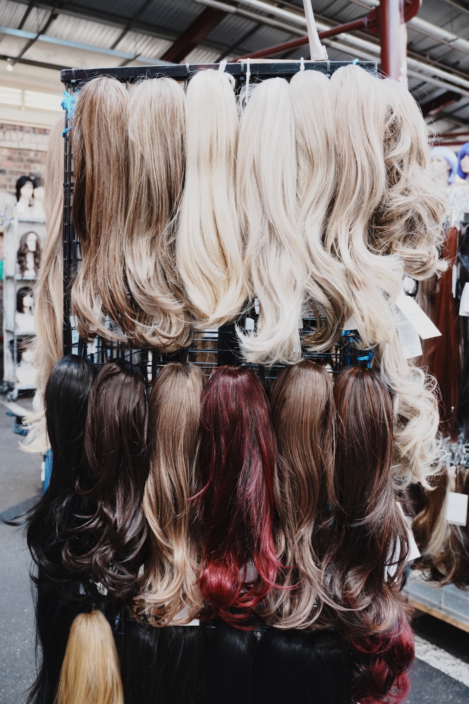 Synthetic wigs in various shades hanging on a retail rack.