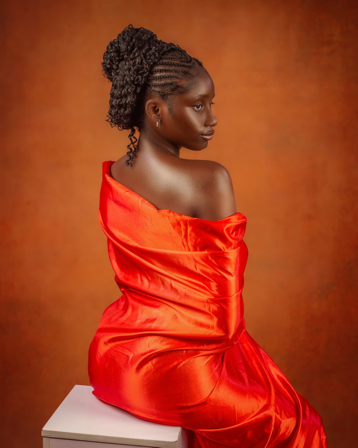 Woman with braided hair wrapped in red silk fabric.