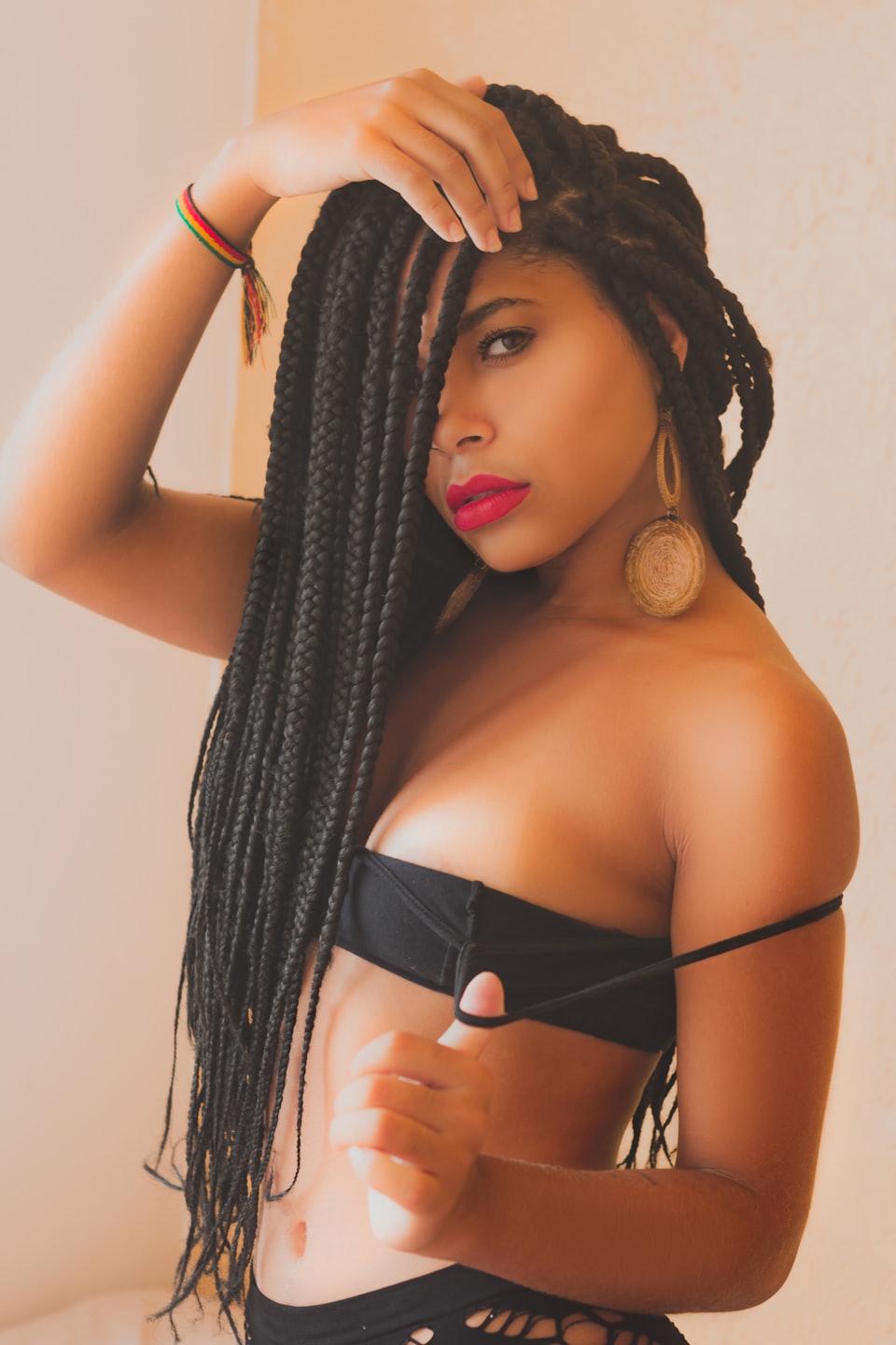 Young Black woman with braided hair, pulling down bra strap.