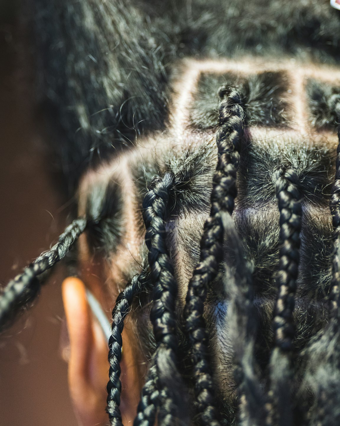 Neatly parted box braids arranged in square sections on a scalp.